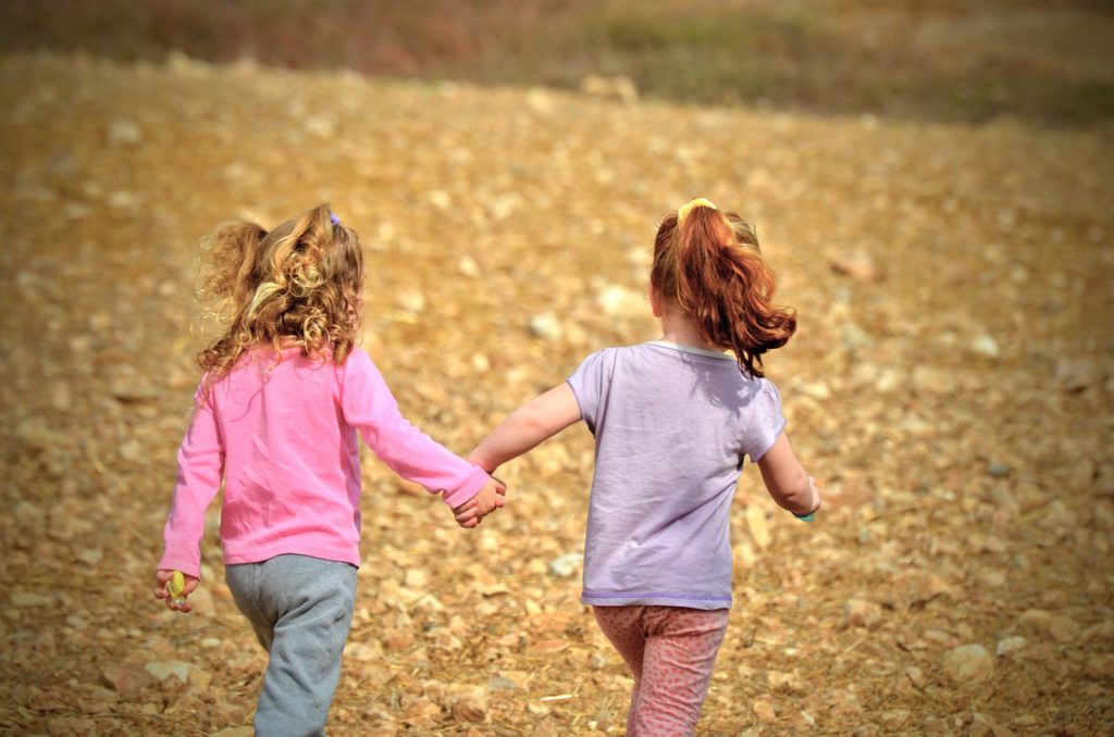 Zwei kleine Mädchen laufen Hand in Hand